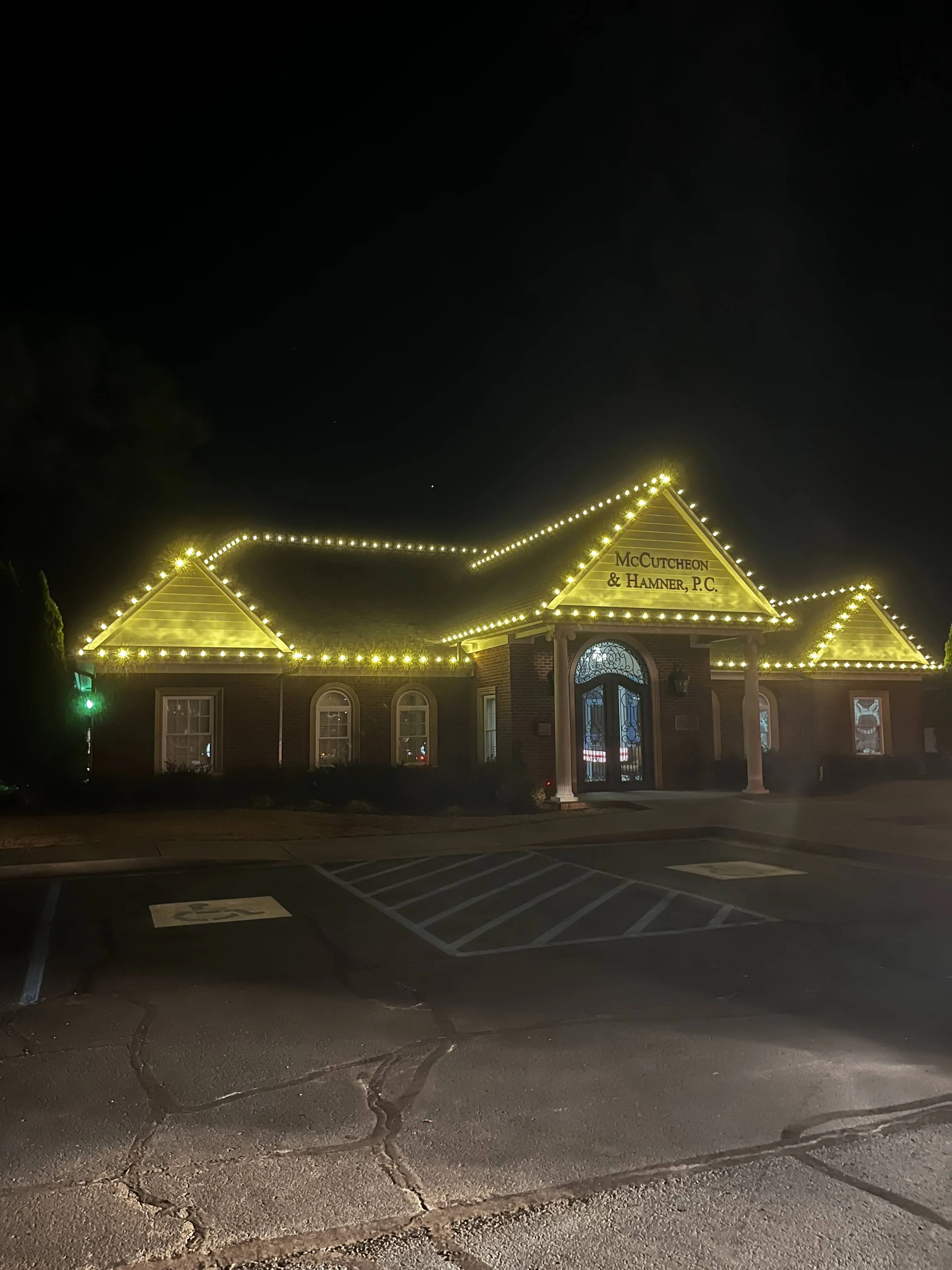 Warm-white Christmas lights installed along a brick building roofline at night