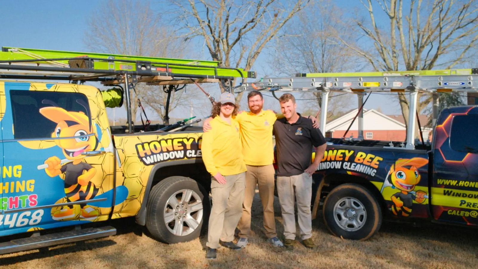 The HoneyBee Window Cleaning crew in front of their two branded trucks