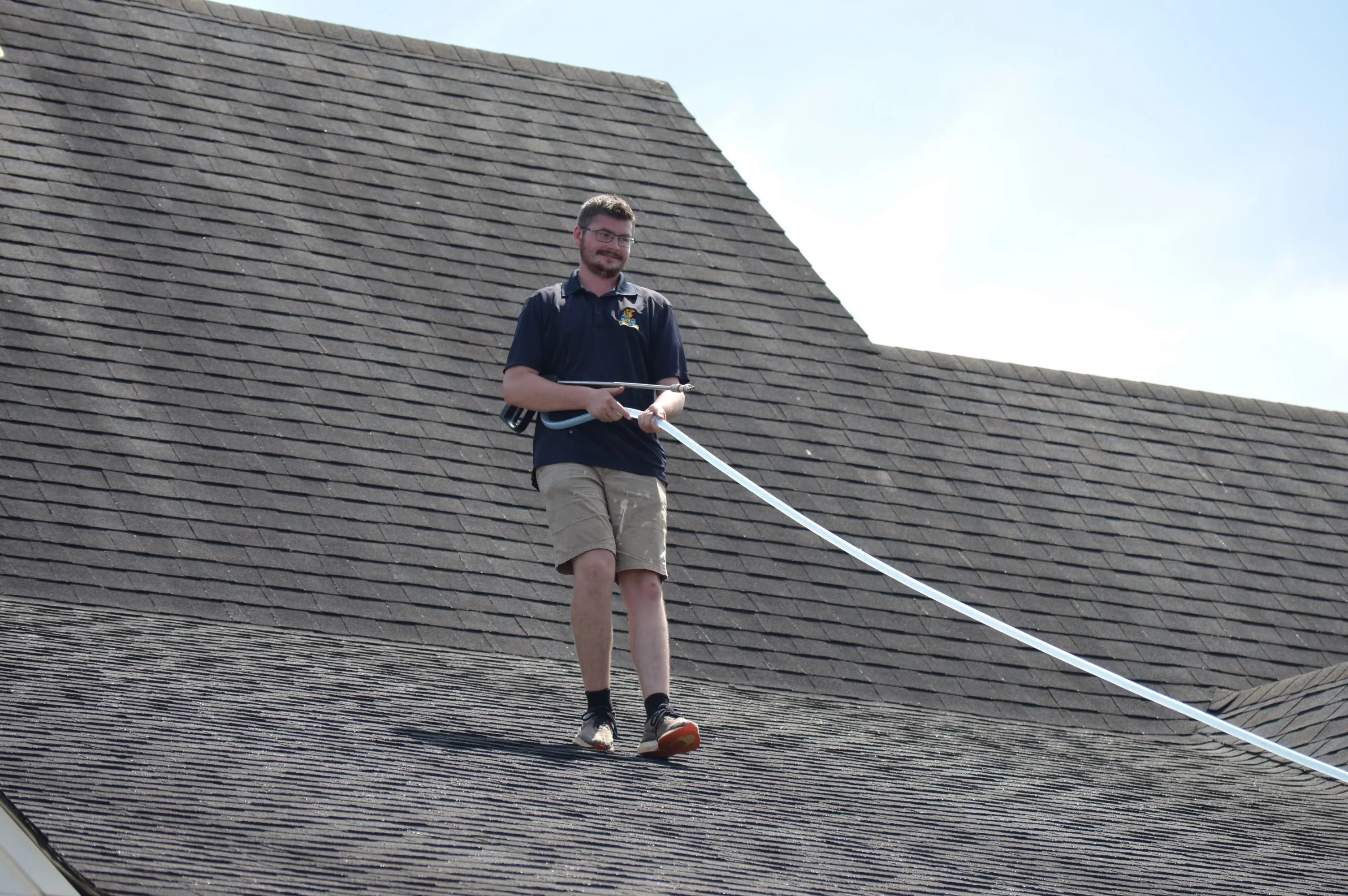 HoneyBee technician soft-washing a shingle roof