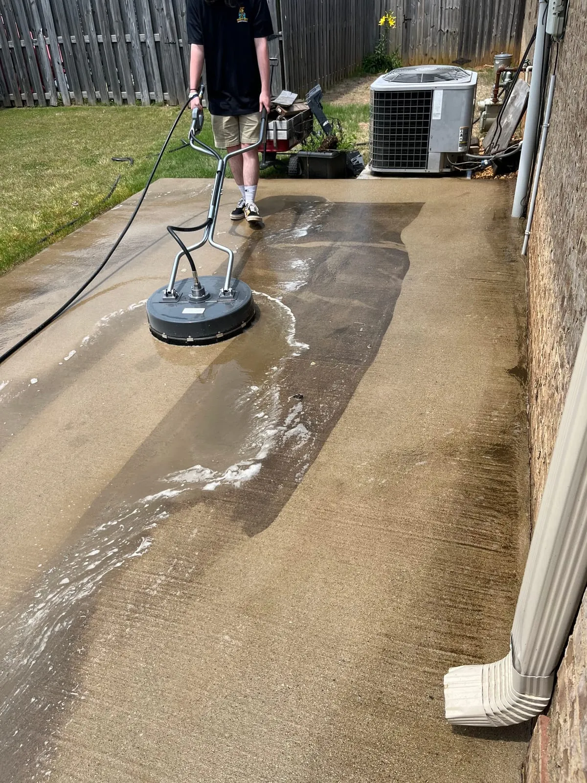 Surface cleaner restoring a concrete driveway, clean line visible
