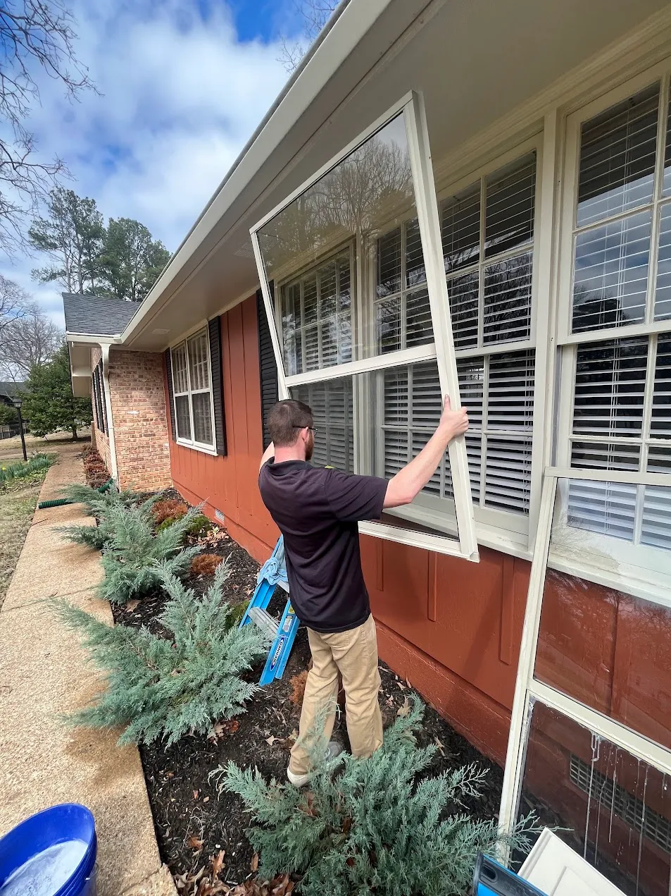 HoneyBee technician lifting a storm window out of its frame to clean the glass behind it